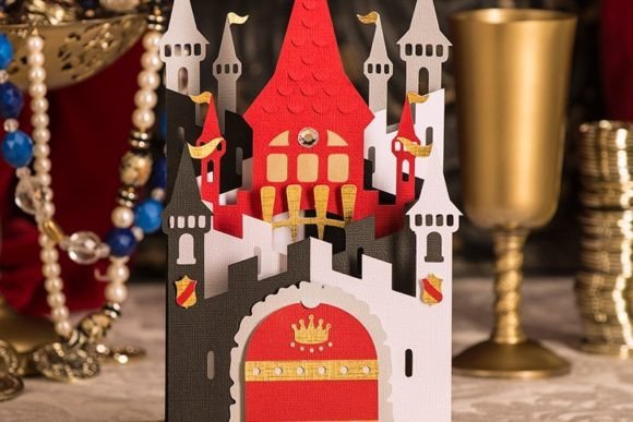 King Of Castle Card 3D - craftkindle: A handcrafted pop-up paper castle card featuring a white and black castle with a striking red central tower, golden accents, and decorative flags. The card is displayed against a background with pearls and golden decorative elements.